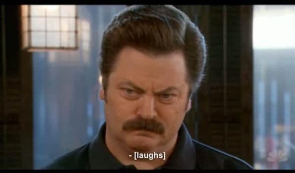 Ron Swanson staring blankly with a caption claiming he is currently laughing.