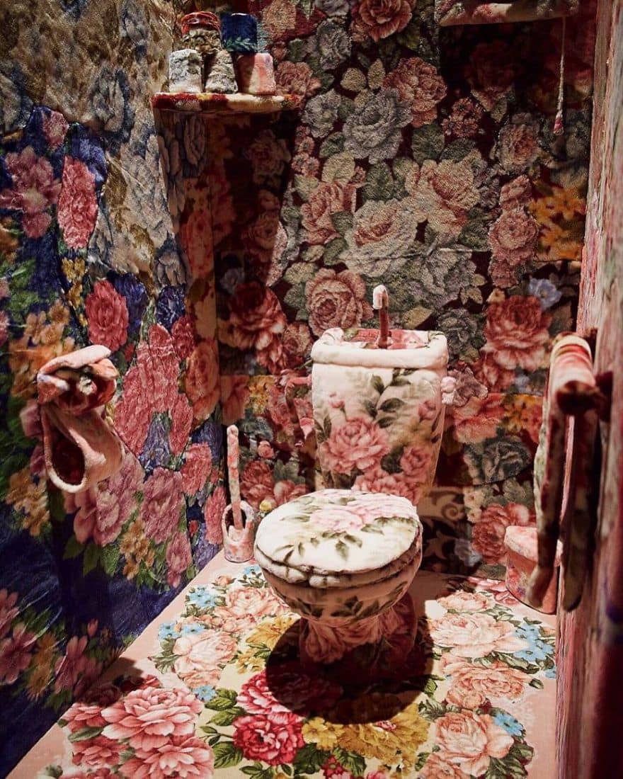 Bathroom completely covered in fuzzy floral carpet including the toilet tank and lid.