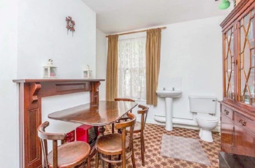 Small dining table jammed in front of a wooden fireplace mantel in a room.