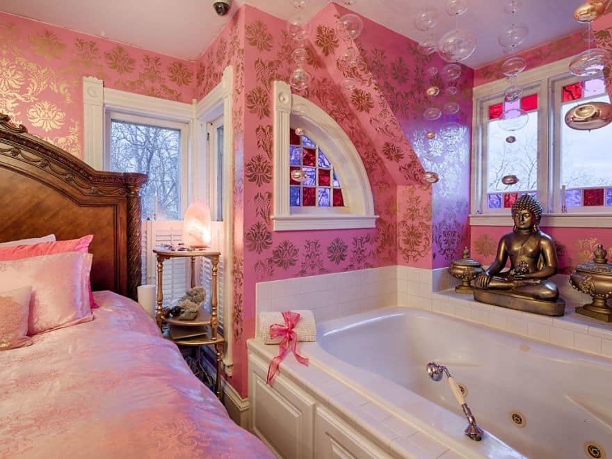 Bedroom with intense pink metallic wallpaper, jacuzzi tub, and a Buddha statue.