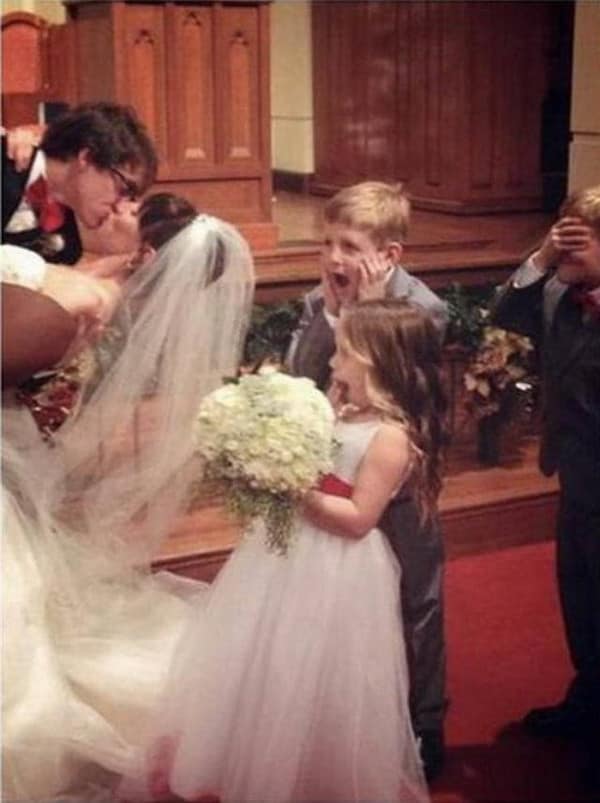 Young boy screaming in horror while bride and groom kiss at altar.