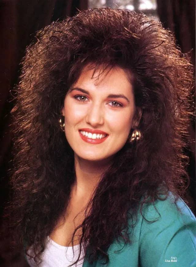 A woman modeling a massive brunette 80s haircut with teased bangs and crimped texture.