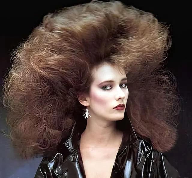 A woman with a polished, blown-out 80s haircut that looks like a mushroom cloud.