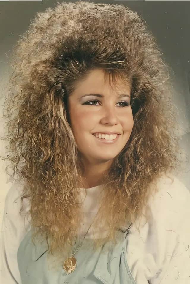 A portrait of a woman with a feathered and teased mullet-style 80s haircut.