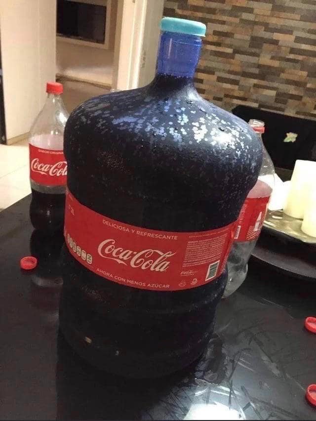 An absolute unit Coca-Cola bottle the size of a water cooler jug sitting on a table