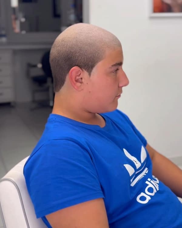A young boy with a buzz cut that has an unnatural blocky hairline haircut fail.