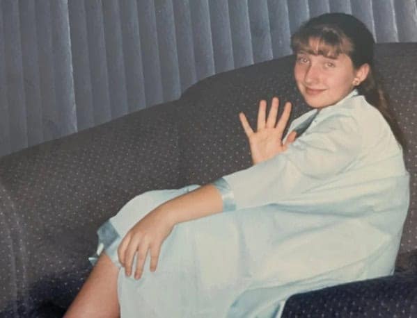 Girl in oversized blue robe waving from couch blunder years.