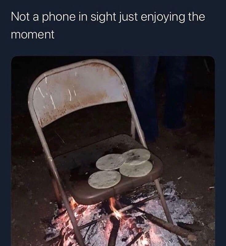 A classic meme photo of tortillas being heated directly on a metal folding chair over a campfire.