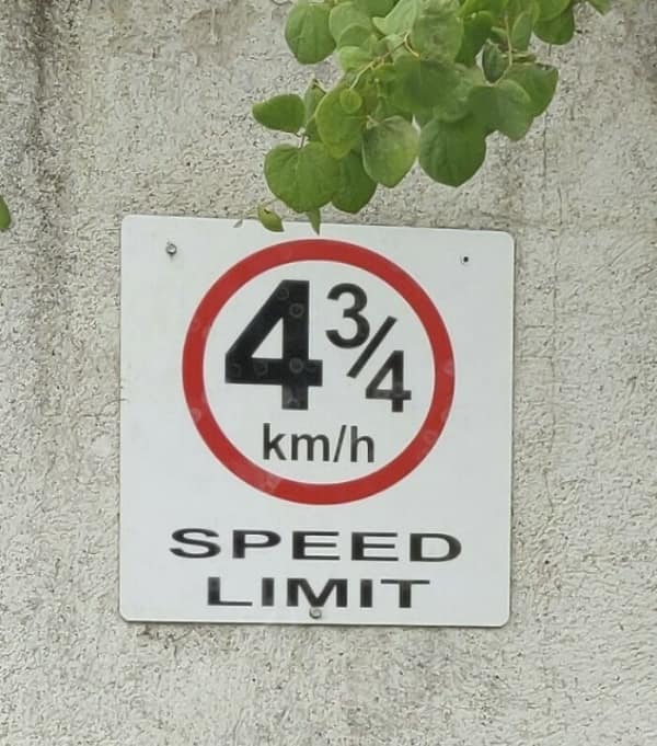 A white speed limit sign showing a fraction of 4 and 3/4 km per hour.