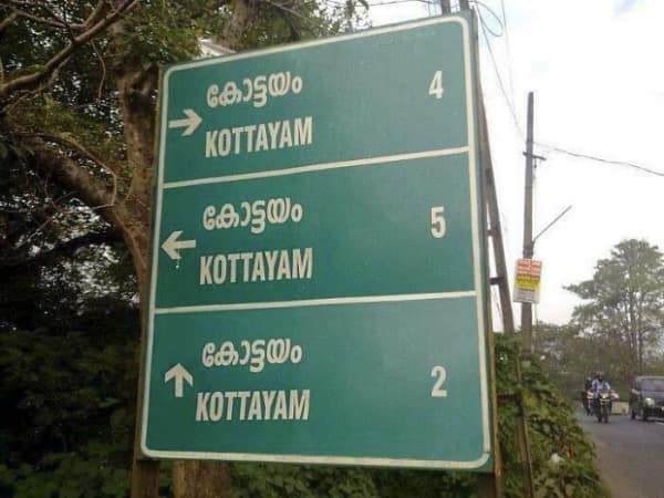 A green road sign showing three different directions all leading to Kottayam at different distances