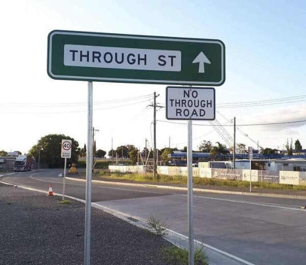 A green sign saying Through St placed directly above a white sign saying No Through Road
