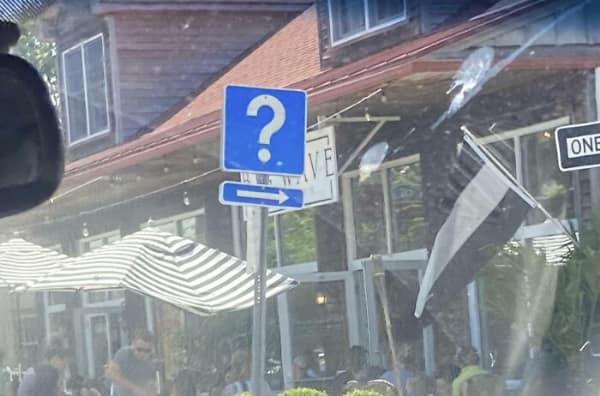 A blue square road sign featuring only a large white question mark above an arrow.