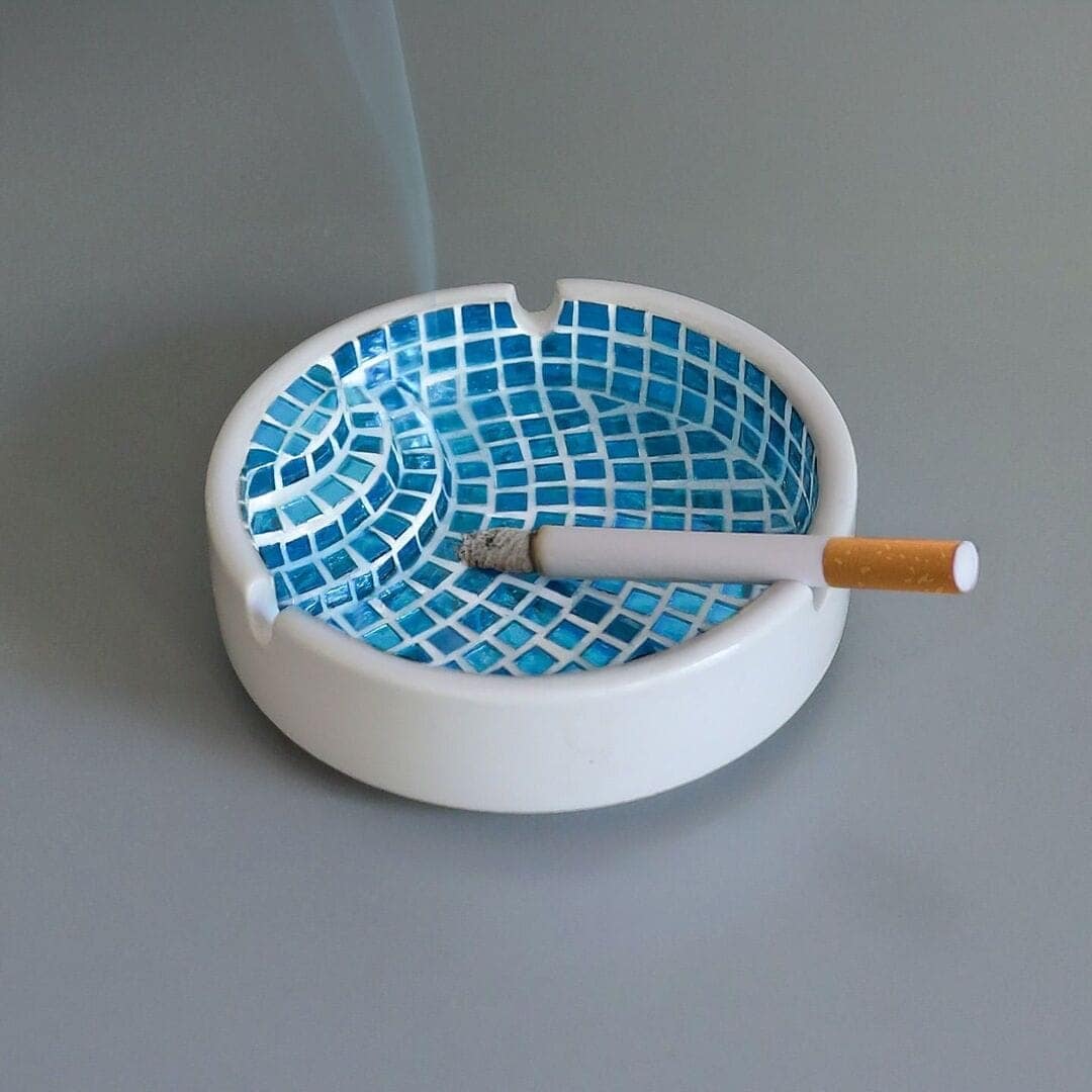 A ceramic ashtray designed to look like a miniature blue tiled swimming pool with stairs.