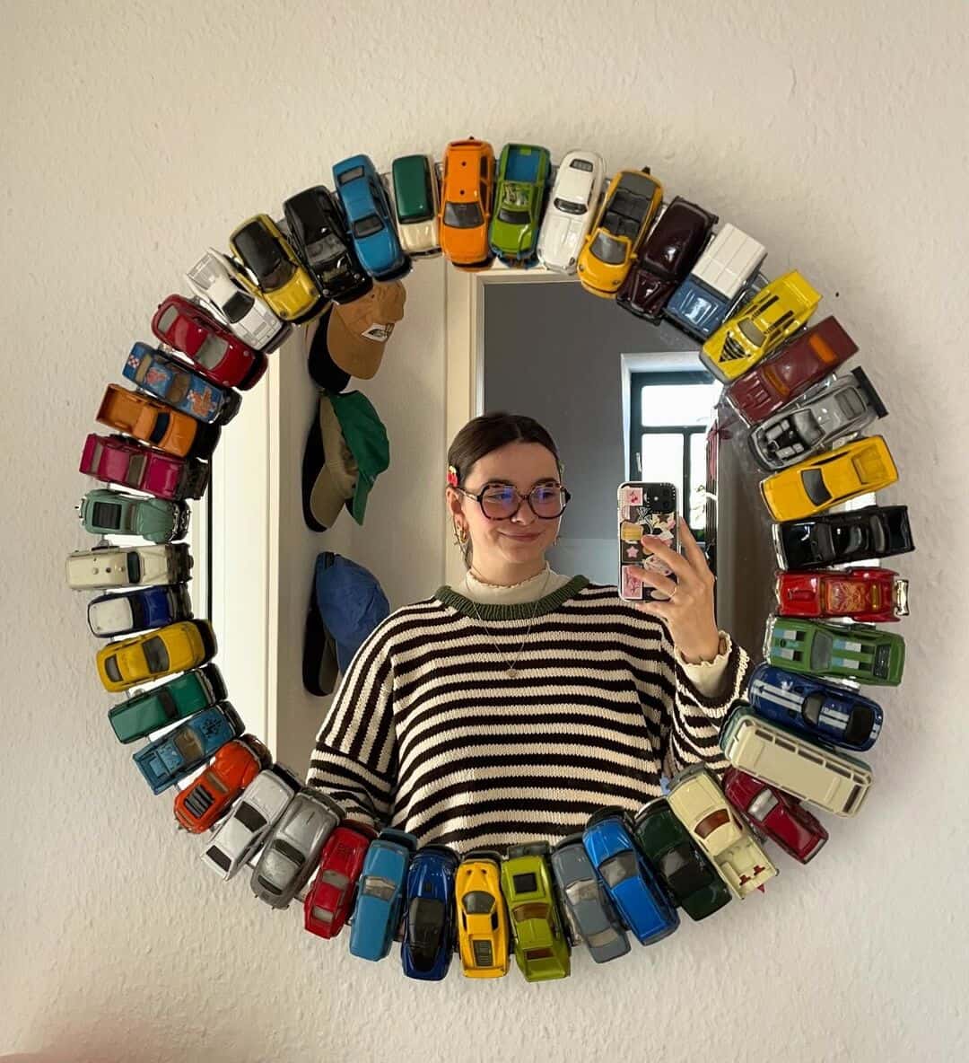 A cool interior design mirror frame made entirely of colorful vintage toy cars arranged in a circle.