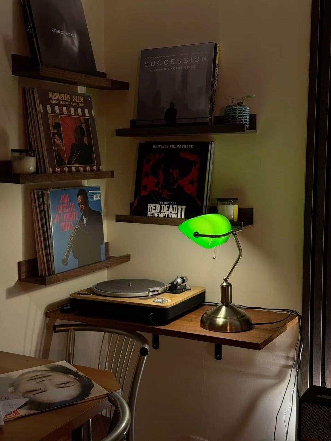 A cool interior design corner with a record player, floating shelves displaying vinyls, and a green lamp.