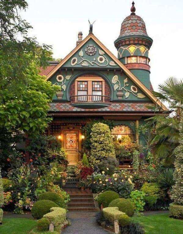 Whimsical green Victorian house with sunflower details and turret cottagecore architecture