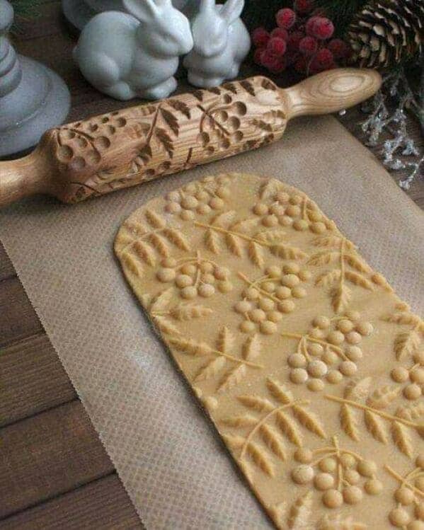 Embossed wooden rolling pin creating leaf patterns on cookie dough cottagecore baking