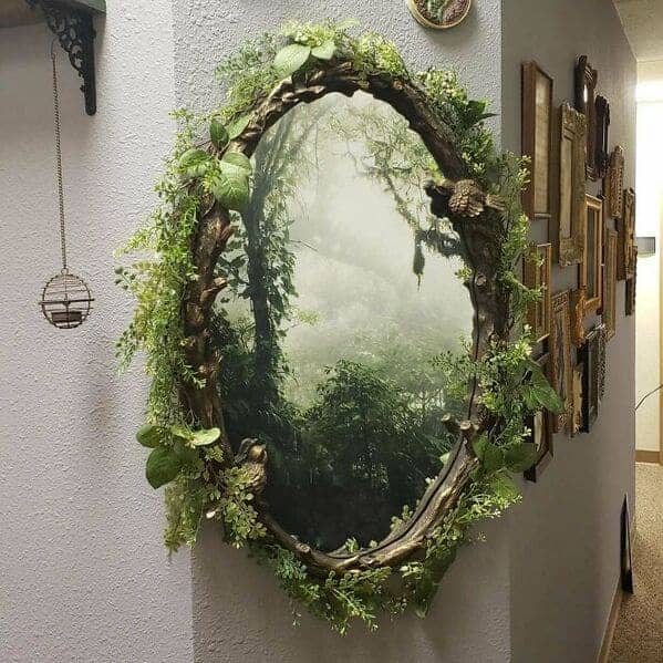 Oval mirror wrapped in moss and branches reflecting foggy forest cottagecore decor