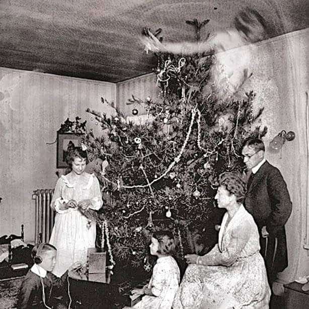 Family gathering around a Christmas tree with a ghostly transparent woman floating near the ceiling.