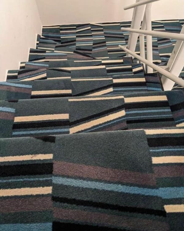A cursed image of a staircase covered in a striped carpet pattern that creates an optical illusion, making the steps invisible.
