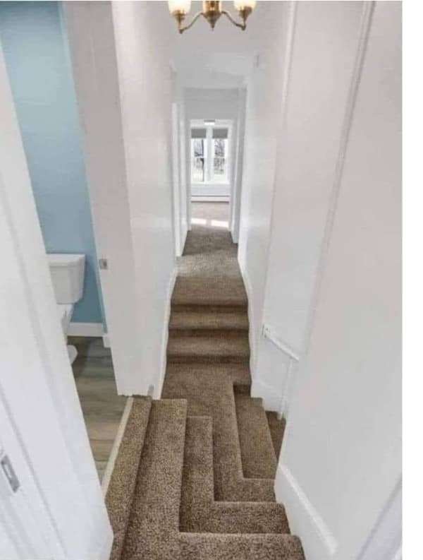 A cursed image of a narrow hallway with carpeted stairs that have a strange, geometric cutout.
