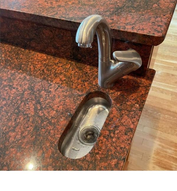A wtf photo showing a kitchen island with an extremely narrow, unusable sink slot.