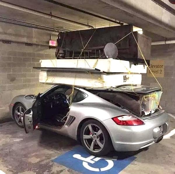 A driving fail showing a silver Porsche sports car with a massive pile of furniture tied to the roof.