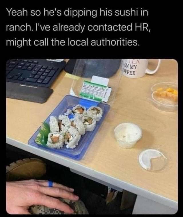 Person dipping sushi roll into ranch dressing cup at office desk.