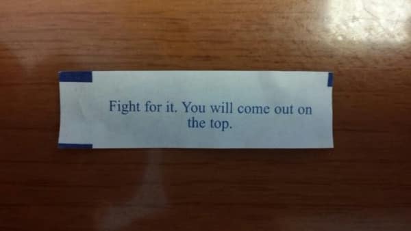 Fortune cookie paper strip saying fight for it you will come out on top.