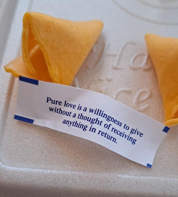Open fortune cookie with message defining pure love as giving without receiving.
