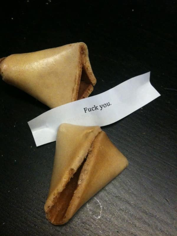 Fortune cookie cracked open to reveal a paper simply saying f word you.