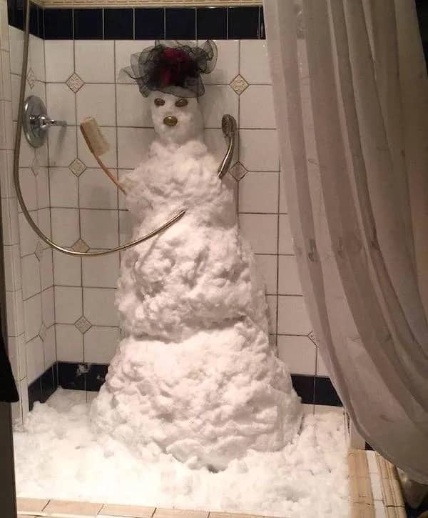 Snowman built inside bathroom shower stall holding loofah and shower head meme.