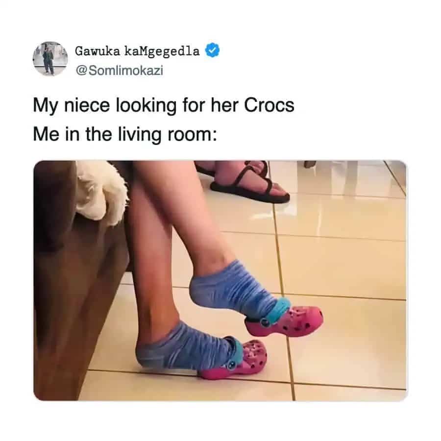 Adult feet squeezed into tiny pink toddler Crocs labeled as niece's shoes.