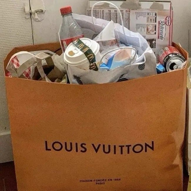 Luxury Louis Vuitton shopping bag filled with McDonald's wrappers, soda cans, and general recycling trash.