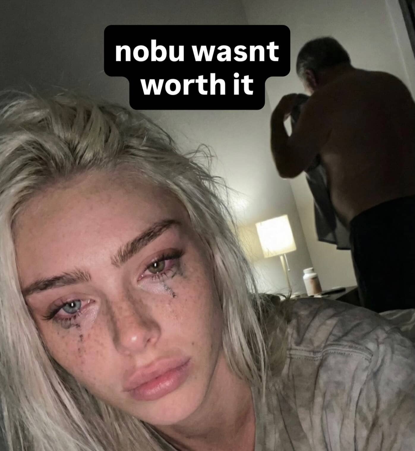 Crying woman selfie with Nobu caption and shirtless man in background.