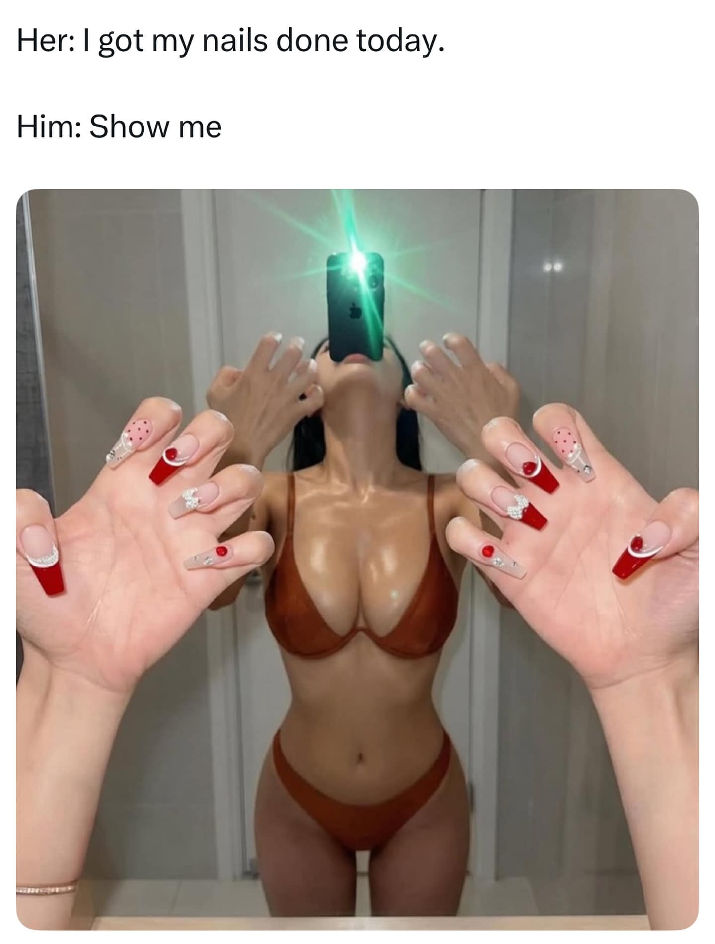 Woman holding phone in mouth with flashlight to show off fresh manicure set.