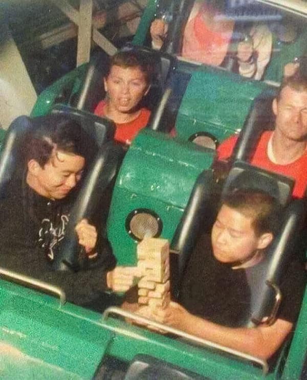 A funny rollercoaster picture showing two men calmly playing a game of Jenga on a moving rollercoaster.