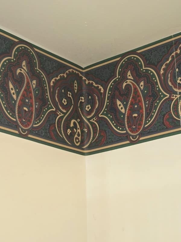 Paisley wallpaper border featuring hunter green, maroon, and beige designs on wall.