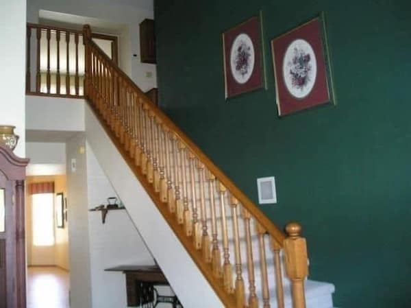 Staircase with hunter green accent wall and framed art with maroon mats.