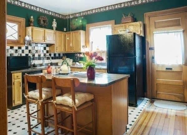 Kitchen featuring hunter green walls, wallpaper border, and light wood cabinetry.
