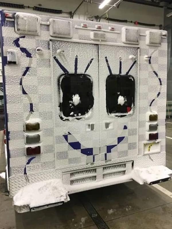 A hilarious meme showing the back of a snow-covered ambulance with a smiley face wiped onto the doors.