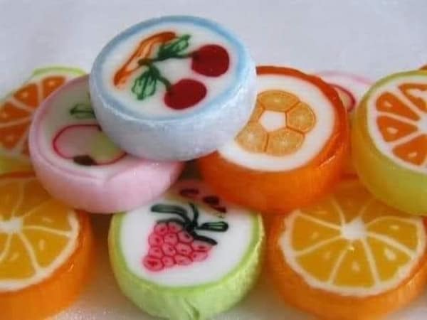 A close up photo of vintage hard candies with fruit designs in the center.