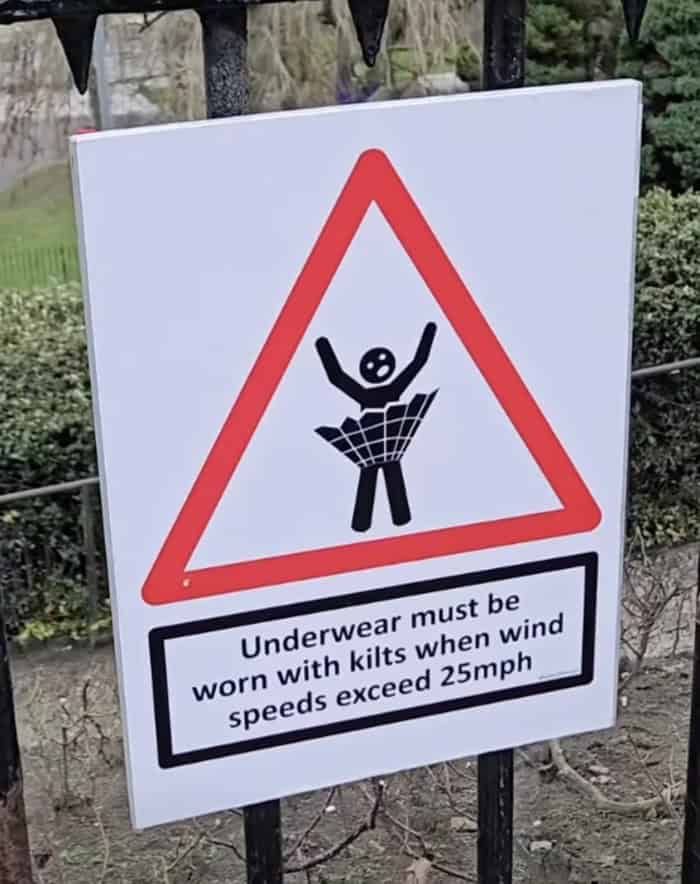 Road warning sign mandating underwear with kilts during high winds.