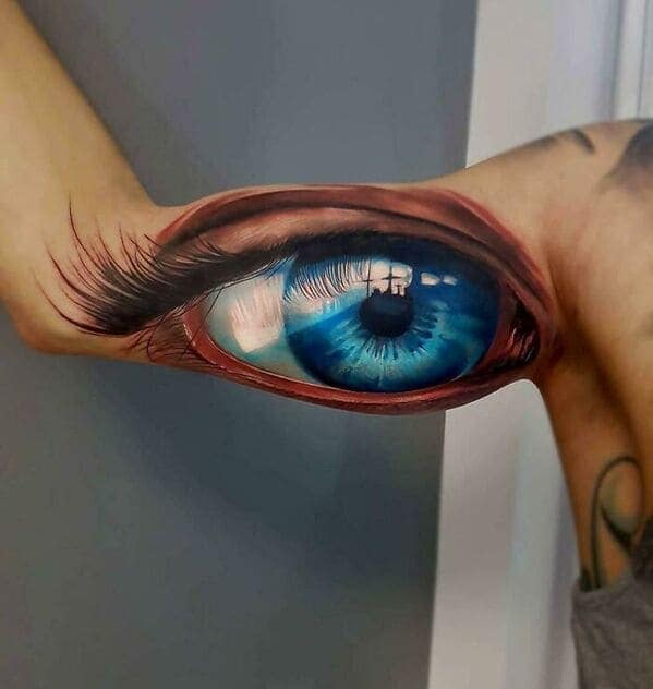 Hyper realistic blue eye tattoo on inner bicep staring intensely questionable tattoos.
