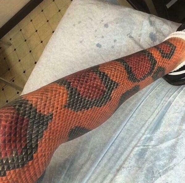 Full leg tattoo of realistic orange and black snake scales questionable tattoos.