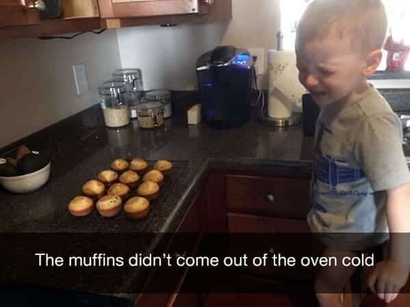 Little boy crying in kitchen because freshly baked muffins are hot instead of cold.