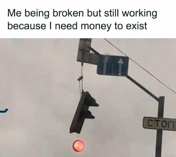 A relatable meme photo of a broken traffic light hanging by a wire but still shining red.