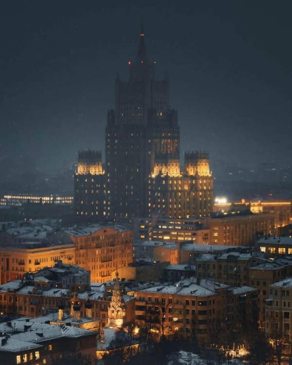 A towering gothic skyscraper at night representing an obvious super villain lair with yellow lights.