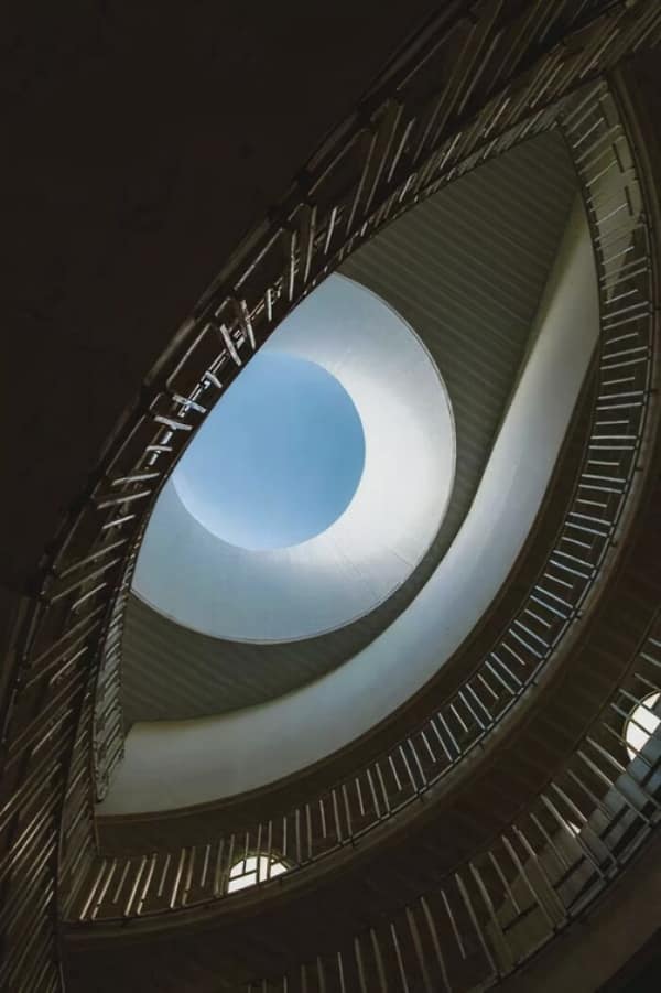 A spiral staircase view looking up that resembles a giant eye in a sinister building.
