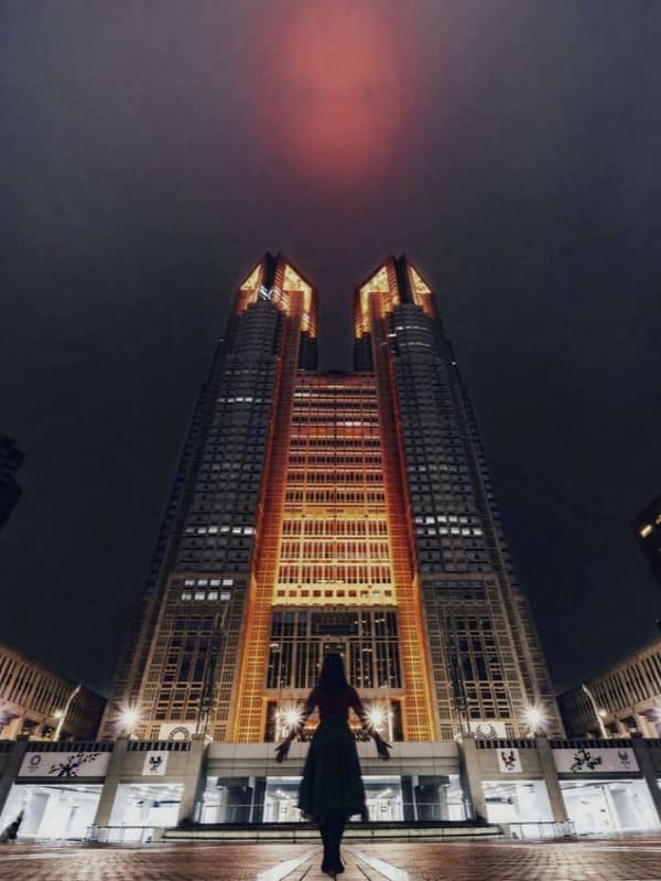 A tall twin tower building lit with orange lights at night, an obvious super villain lair.